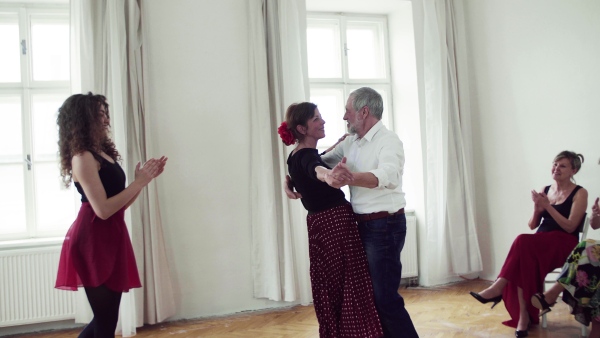 A group of senior people attending dancing class with dance teacher.