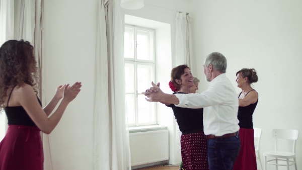 A group of senior people attending dancing class with dance teacher.