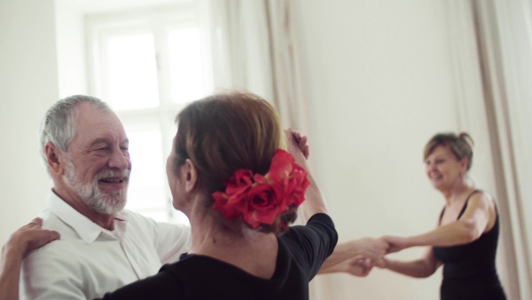 A group of senior people attending dancing class with dance teacher.