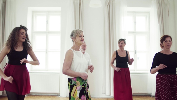 A group of senior people attending dancing class with dance teacher.