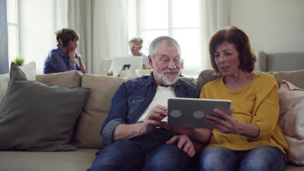 Senior couple using tablet in community center club, technology in everyday life concept.