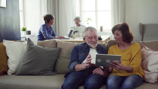 Senior couple using tablet in community center club, technology in everyday life concept.