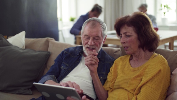 Senior couple using tablet in community center club, technology in everyday life concept.