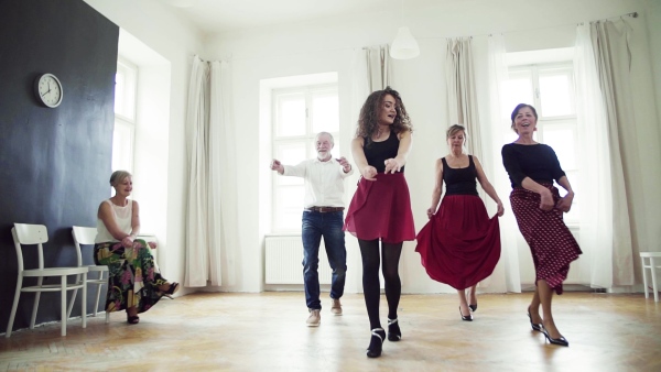 A group of senior people attending dancing class with dance teacher. Slow motion.