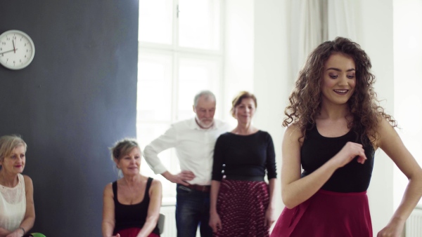 A group of senior people attending dancing class with dance teacher.