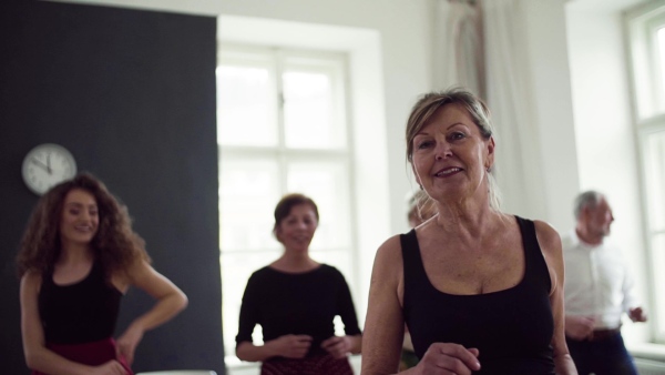 A group of senior people attending dancing class with dance teacher. Slow motion.