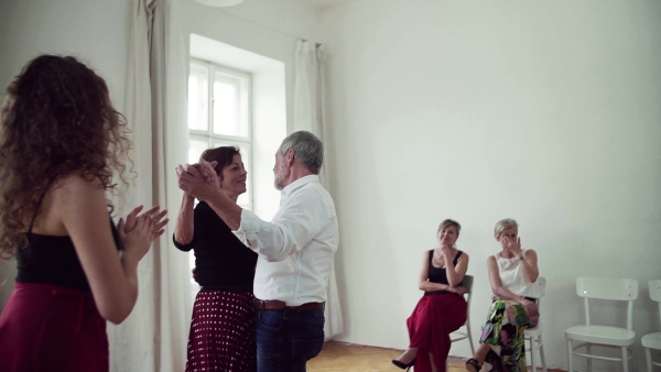 A group of senior people attending dancing class with dance teacher. Slow motion.