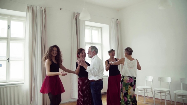 A group of senior people attending dancing class with dance teacher. Slow motion.