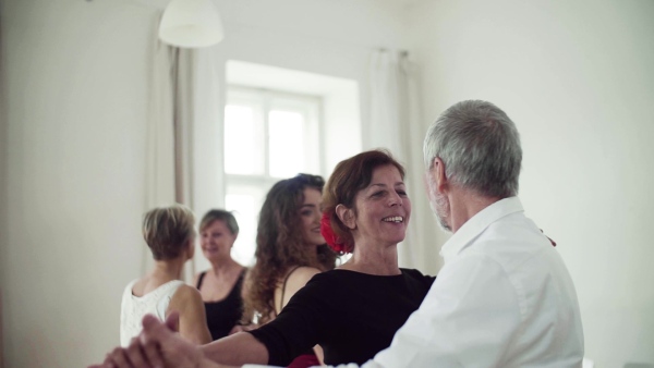 A group of senior people attending dancing class with dance teacher. Slow motion.