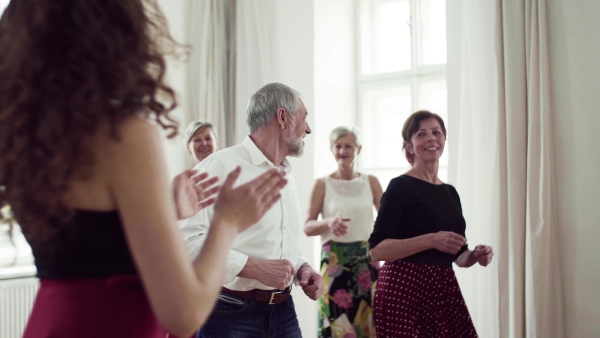 A group of senior people attending dancing class with dance teacher.