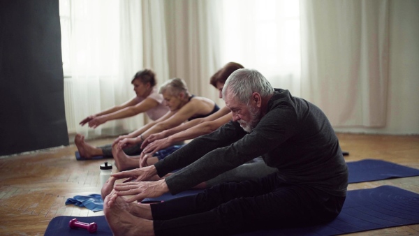 Group of active senior people doing exercise in community center club. Slow motion.