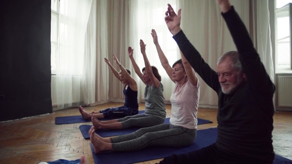 Group of active senior people doing exercise in community center club. Slow motion.