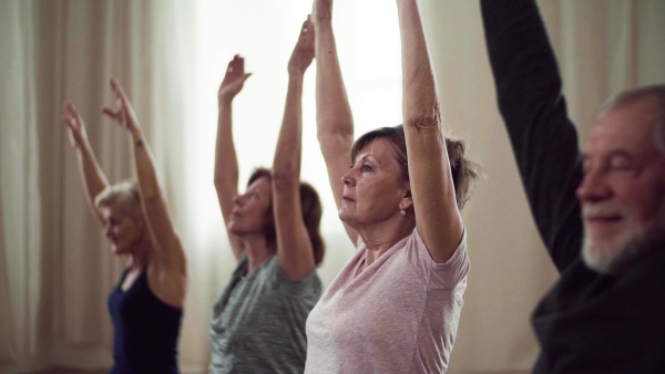 Group of active senior people doing exercise in community center club. Slow motion.