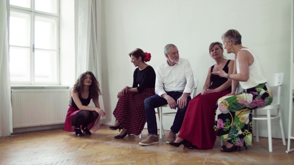 A group of senior people attending dancing class talking to a dance teacher.