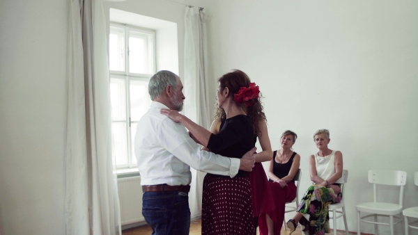 A group of senior people attending dancing class with dance teacher.