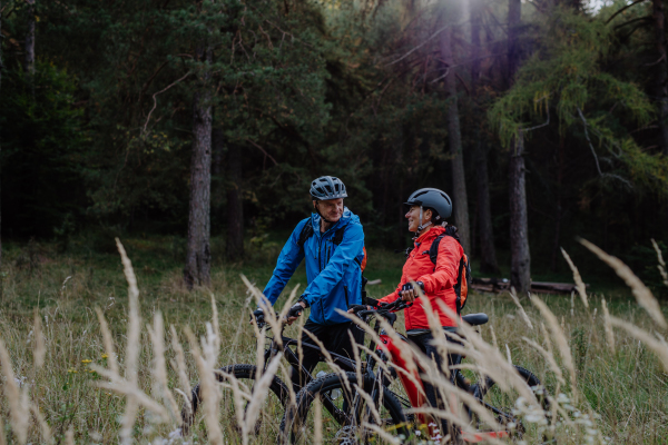 A happy senior couple bikers embracing outdoors in nature in autumn day.