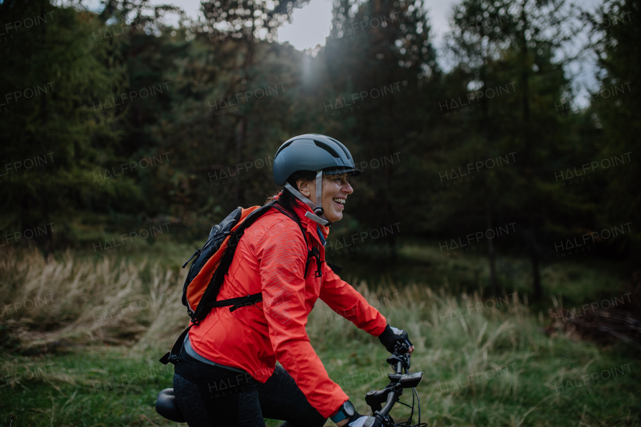 An active senior woman biker riding bike in nature on autumn day.