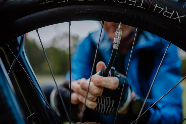 A close-up of a man pumping bicycle wheel in nature.