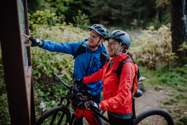 A happy senior couple bikers resting outdoors in nature in autumn day.