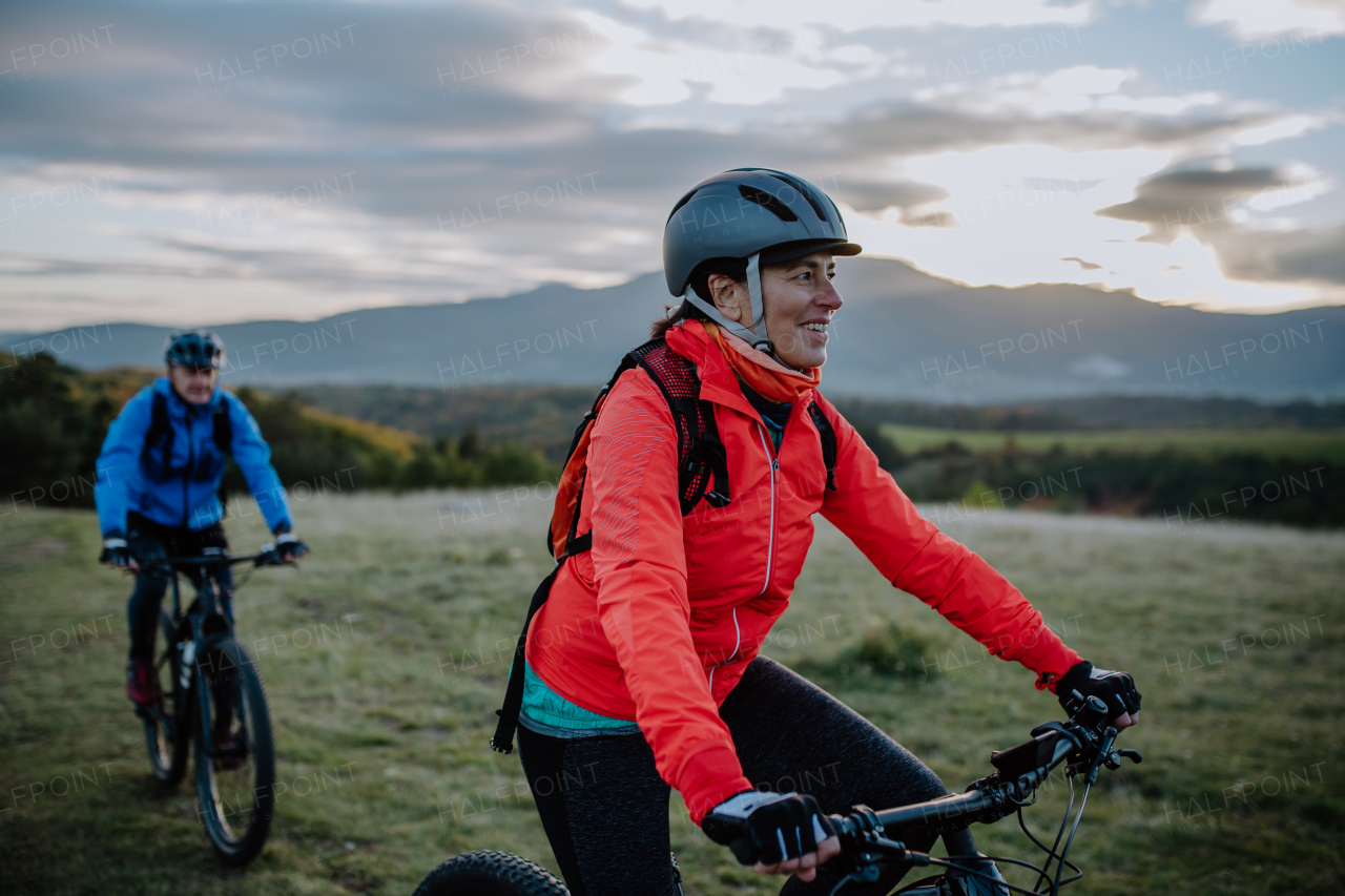 An active senior couple riding bikes outdoors in forest in autumn day.