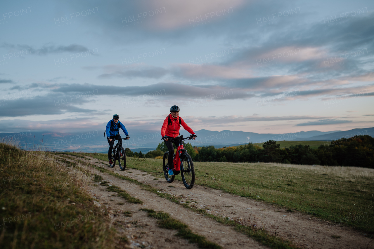 An active senior couple riding bikes outdoors in nature in autumn day.