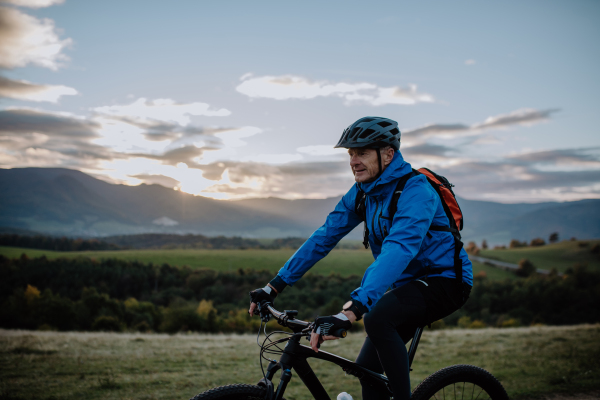 An active senior man biker riding bike in nature on autumn day.