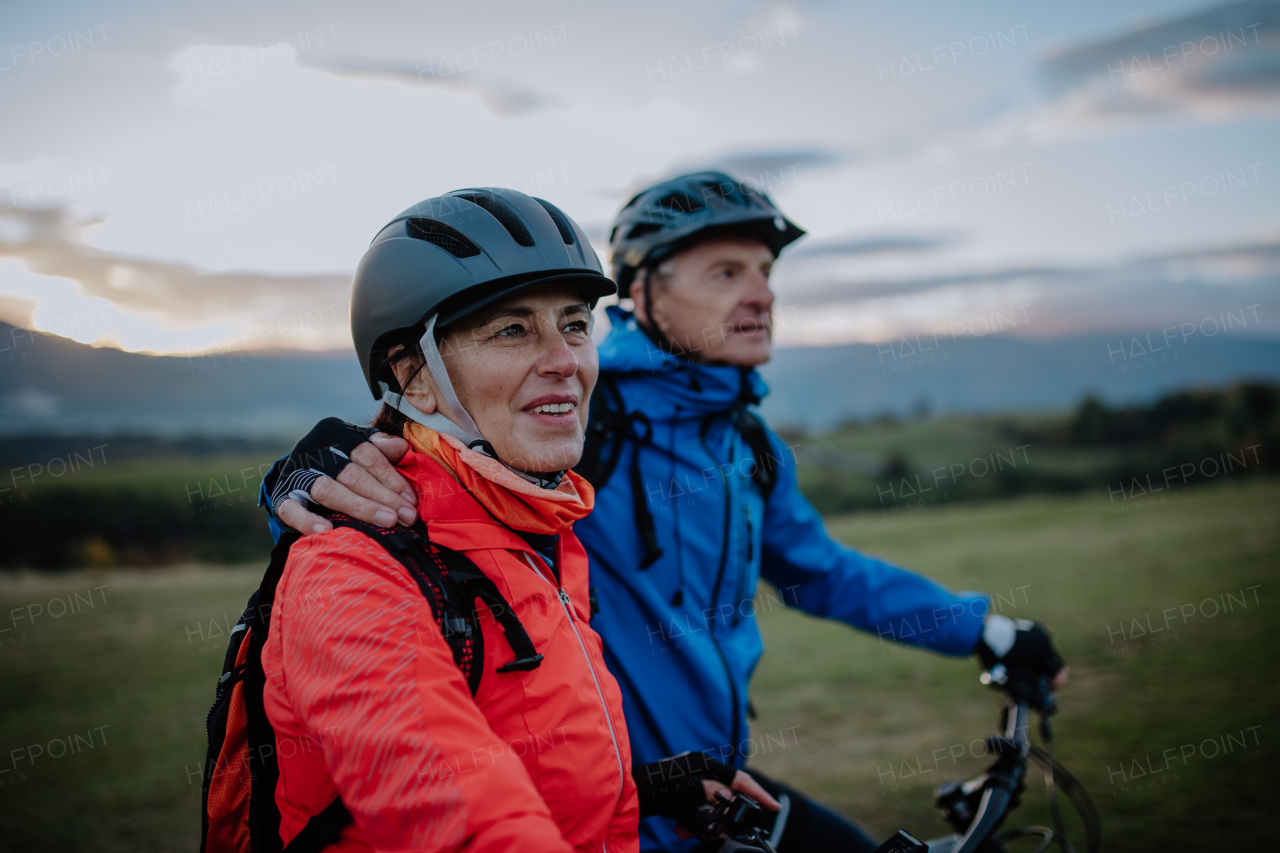 An active senior couple riding bikes outdoors in forest in autumn day.