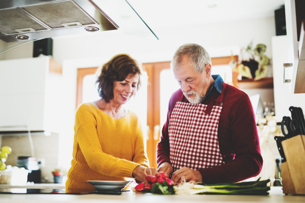 Senior couple preparing food in the kitchen. An old man and woman inside the house.