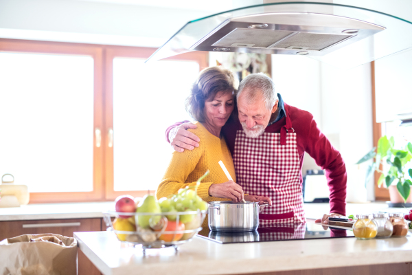 Senior couple preparing food in the kitchen. An old man and woman inside the house cooking.