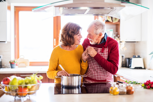 Senior couple preparing food in the kitchen. An old man and woman inside the house, cooking.