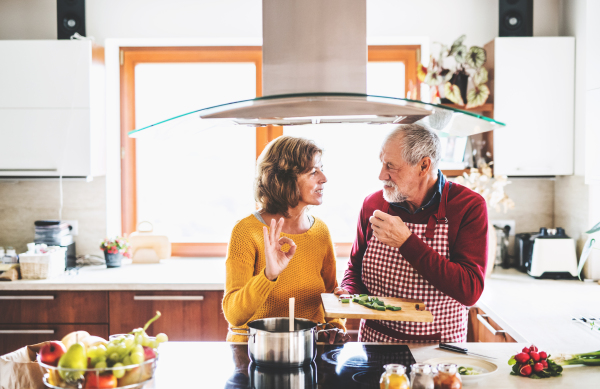 Senior couple preparing food in the kitchen. An old man and woman inside the house.