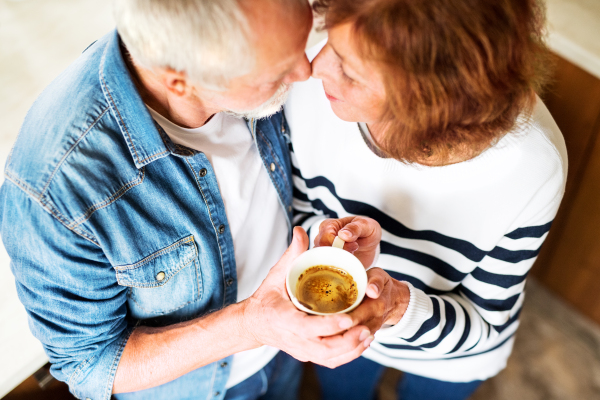 Senior couple at home. An old man and woman inside the house, holding a cup of coffee. Top view.