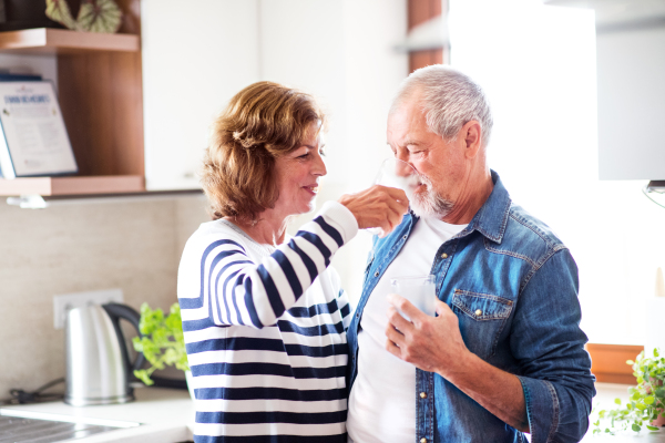 Senior couple at home. An old man and woman inside the house, drinking water.