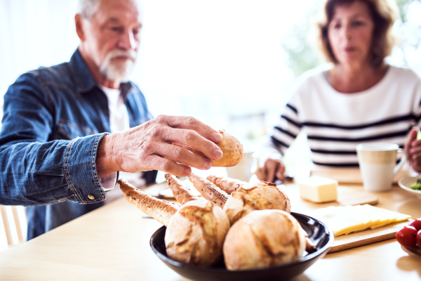 Senior couple eating breakfast at home. An old man and woman sitting at the table, eating breakfast.