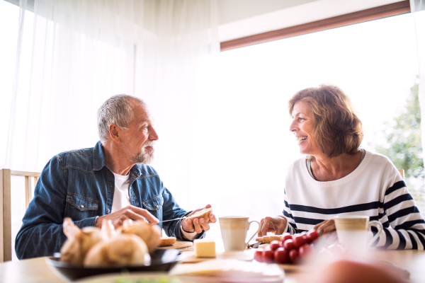 Senior couple eating breakfast at home. An old man and woman sitting at the table, eating breakfast.