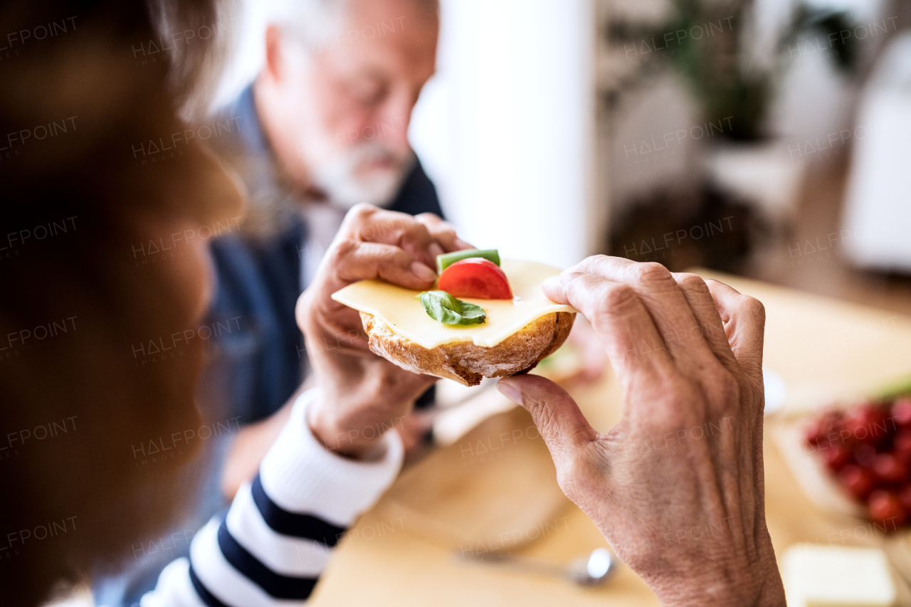 Unrecognizable senior couple eating breakfast at home. An old man and woman sitting at the table.