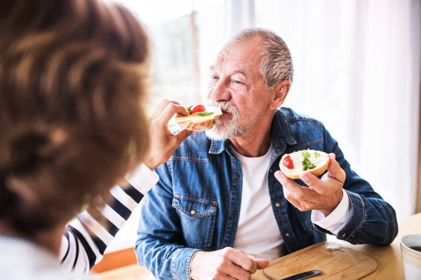 Senior couple eating breakfast at home. An old man and woman sitting at the table, eating breakfast.