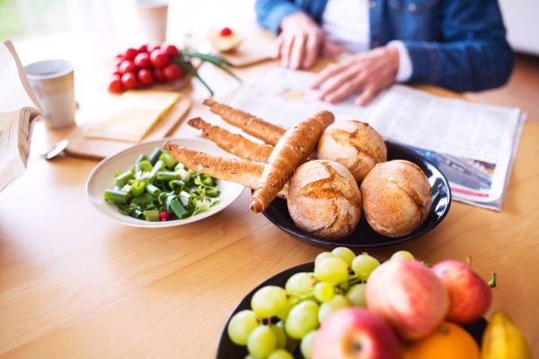 Unrecognizable senior couple eating breakfast at home. An old man and woman sitting at the table, relaxing.