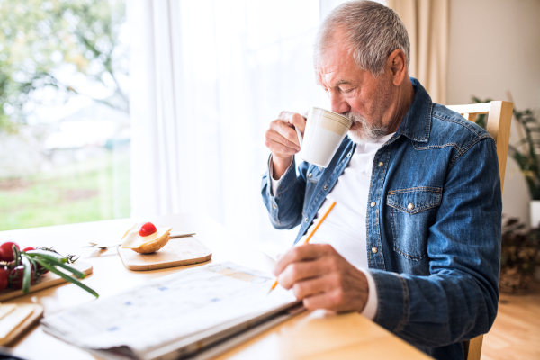 Senior man eating breakfast at home. An old man sitting at the table, relaxing.