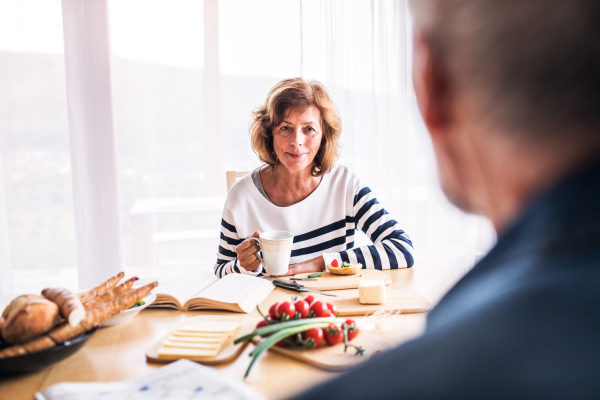 Senior couple eating breakfast at home. An old man and woman sitting at the table, eating breakfast.