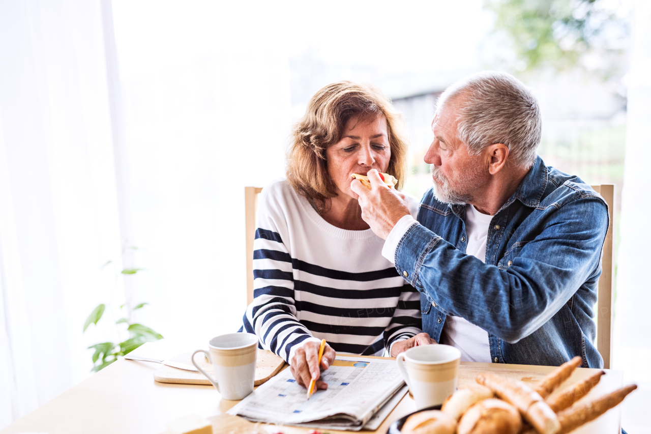 Senior couple eating breakfast at home. An old man and woman sitting at the table, eating breakfast.