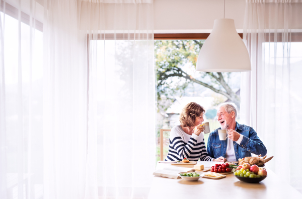 Senior couple eating breakfast at home. An old man and woman sitting at the table, relaxing.