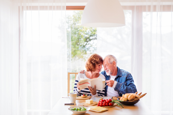 Senior couple eating breakfast at home. An old man and woman sitting at the table, relaxing.