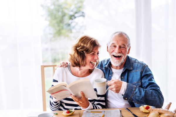 Senior couple eating breakfast at home. An old man and woman sitting at the table, relaxing.