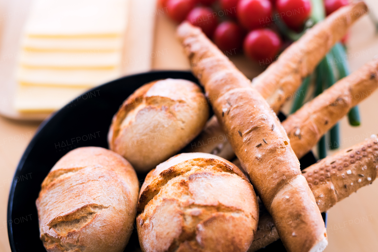 Composition of food on the table. Bread buns, bread sticks, cheese and vegetables on the table. Close up.