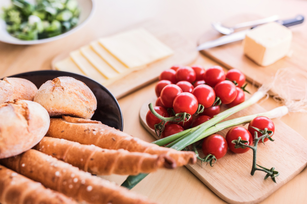 Composition of food on the table. Bread buns, bread sticks, cheese and vegetables on the table. Close up.