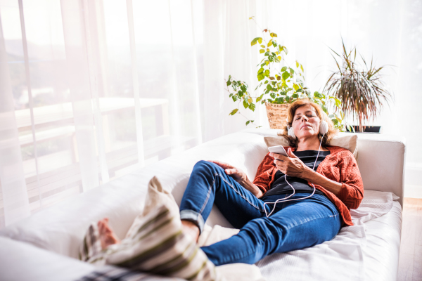 Senior woman relaxing at home, listening to music.