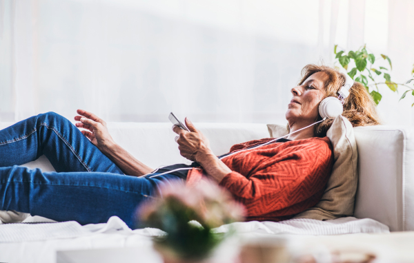 Senior woman relaxing at home, listening to music.