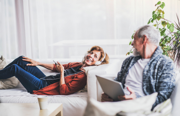 Happy senior couple with tablet and smartphone relaxing at home.