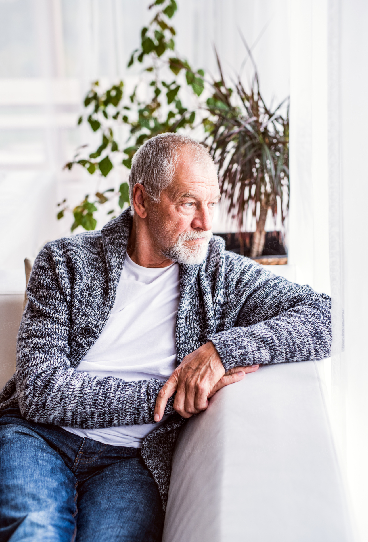 Sad senior man sitting on the sofa at home, relaxing.